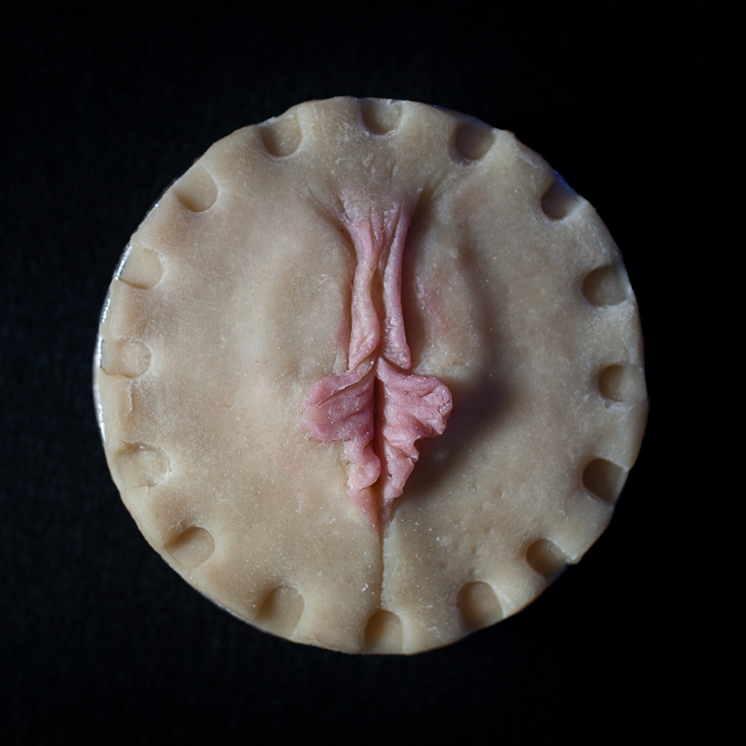 A pie with pie crust art that looks like a human vulva with pink inner labia protruding to demonstrate vulva diversity