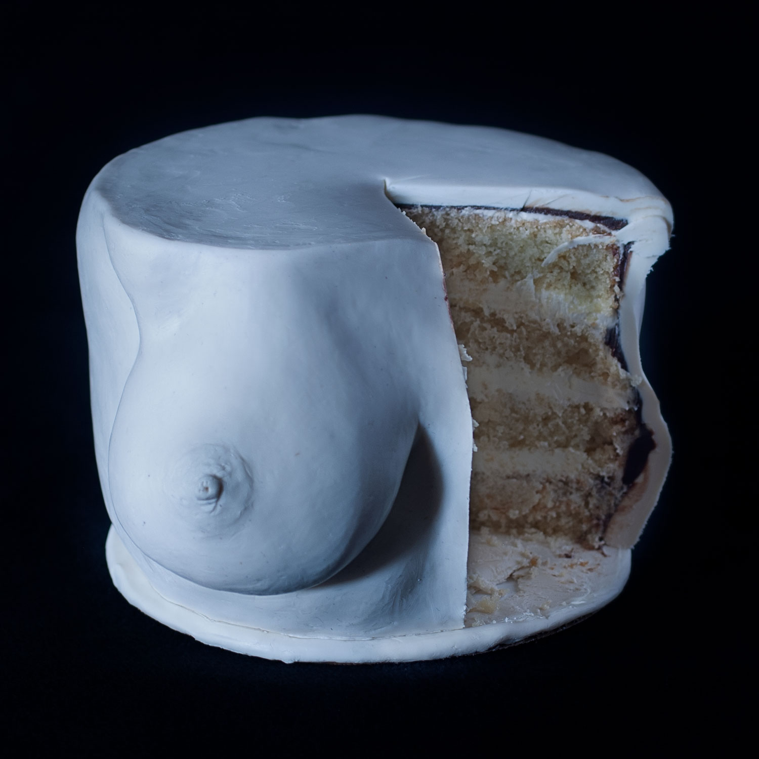 A cake sculpted to look like a woman's breast with a slice removed. 