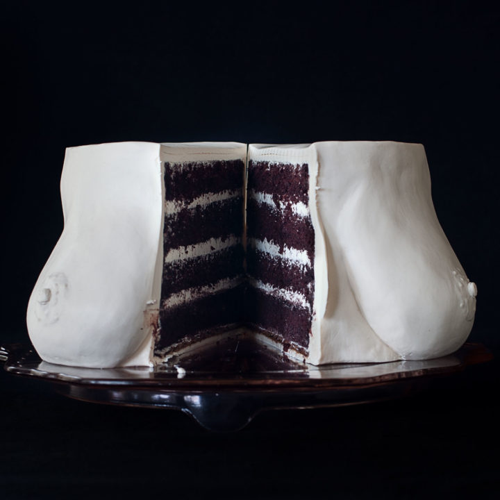 4 layer chocolate cake with vanilla swiss meringue buttercream, decorated to look like realistic breasts. The cake is cut in half down the center and separated exposing the interior of the cake.