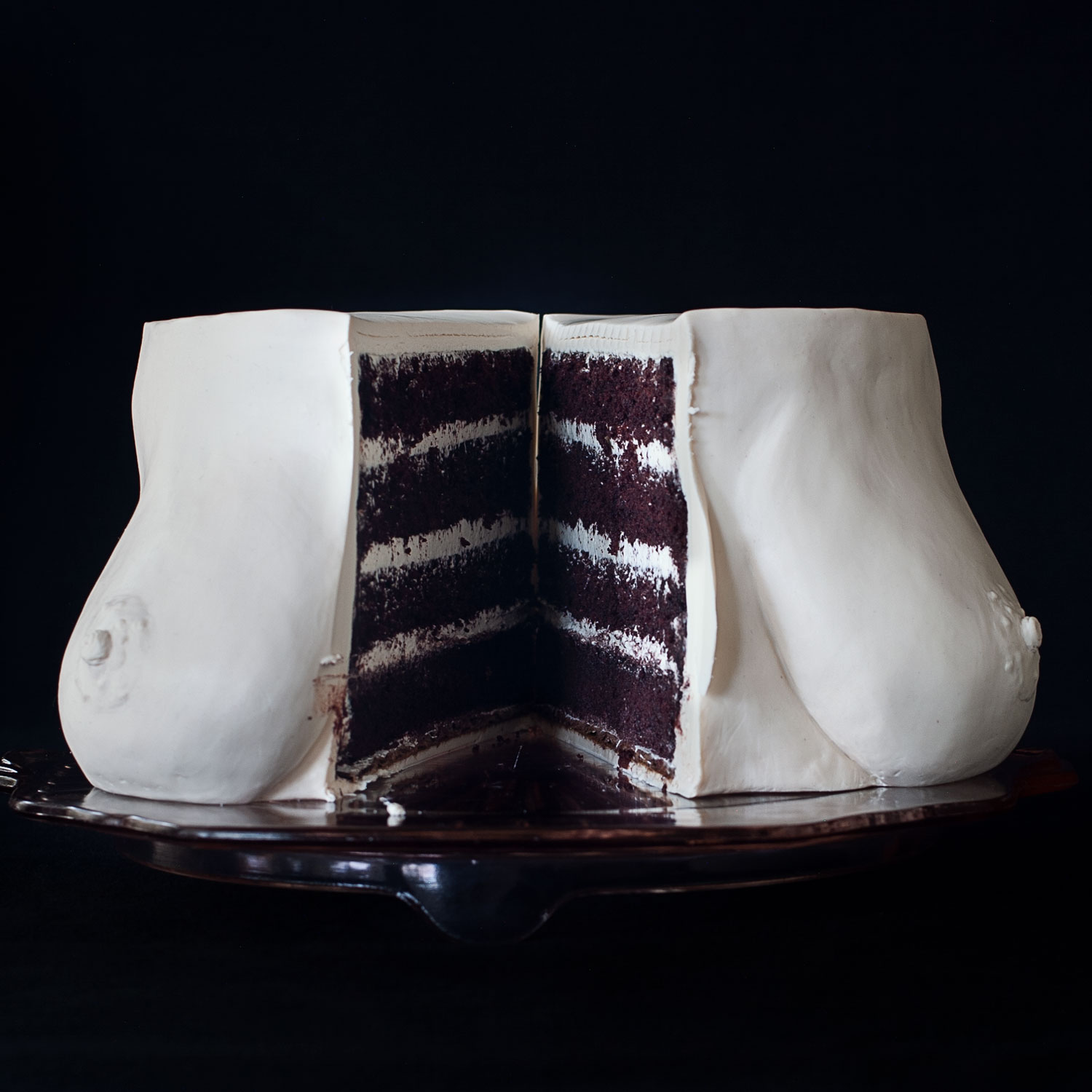 4 layer chocolate cake with vanilla swiss meringue buttercream, decorated to look like realistic breasts. The cake is cut in half down the center and separated exposing the interior of the cake. 