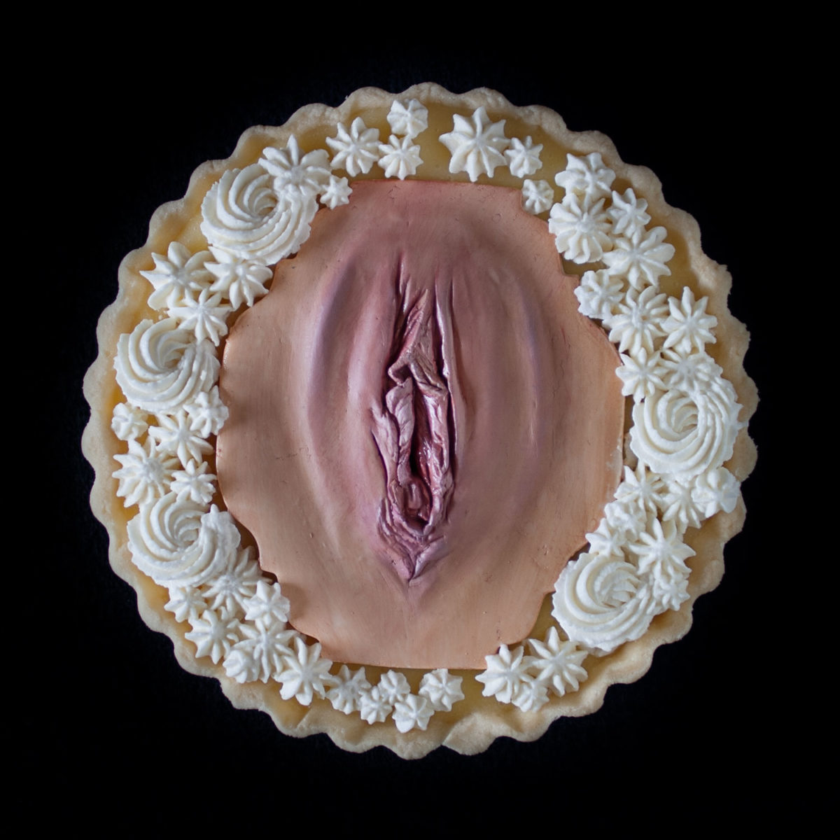 A lemon cream tart with Chantilly cream, decorated with a hand sculpted modeling chocolate vulva as part of a series of vulva tarts.