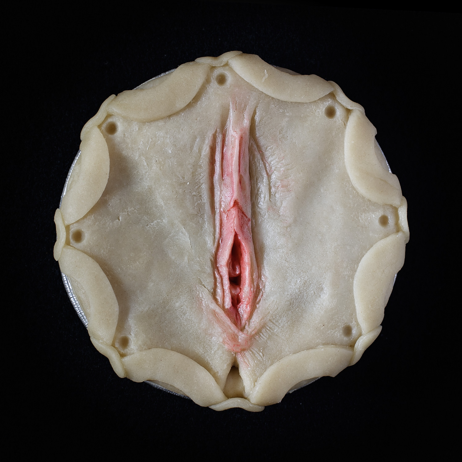 Unbaked Blueberry Pie with pie crust art made that looks like a pink vulva. 