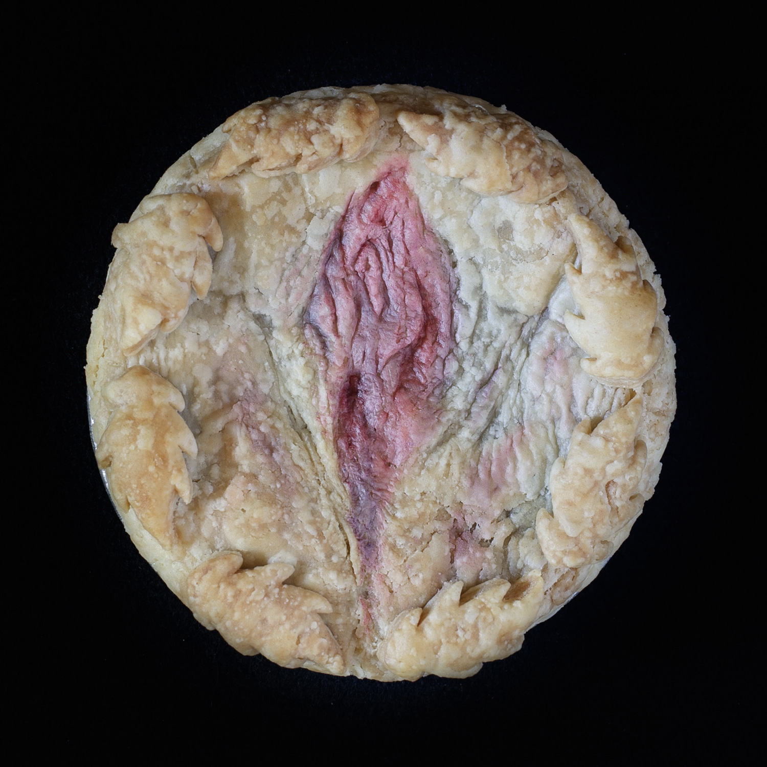 Hand sculpted vulva art on a real, baked cherry pie on a black background