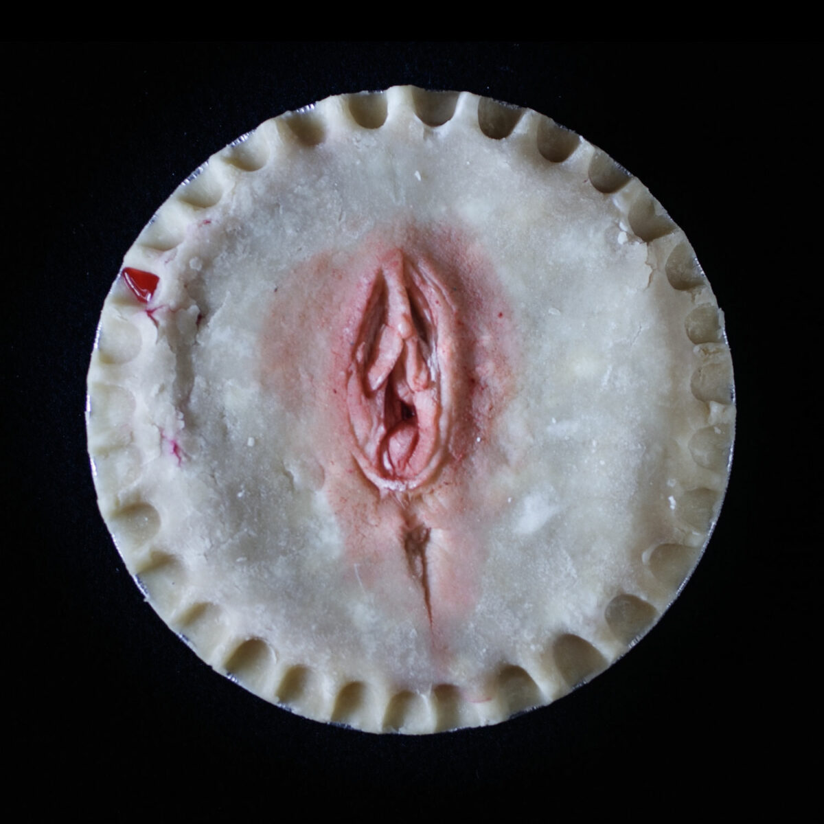 Hand made pie art that looks like a human vulva on a black background.