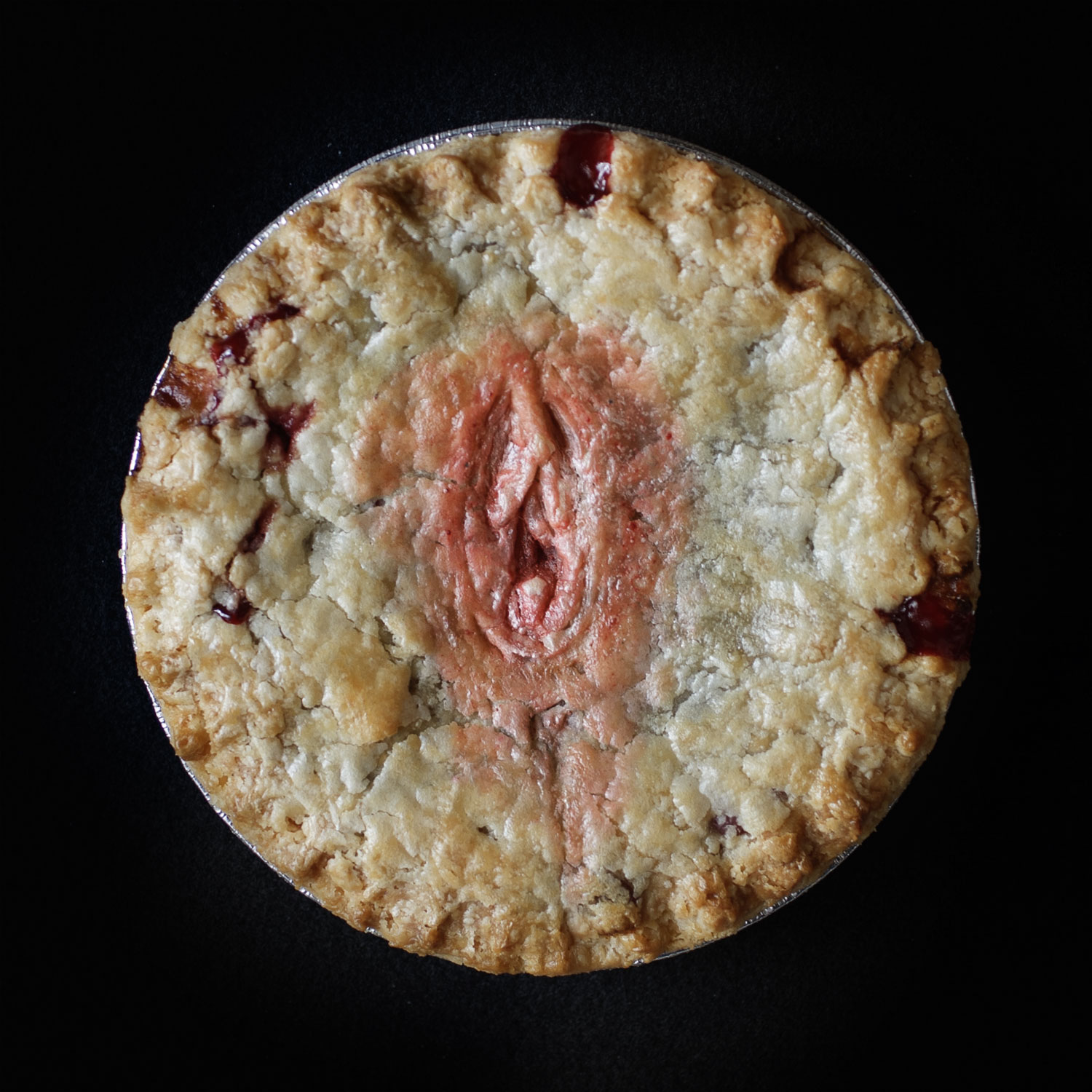 Hand made pie art that looks like a human vulva on a black background.