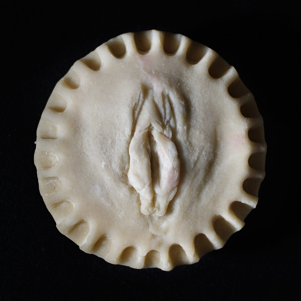 Made from scratch vulva pie on black background.