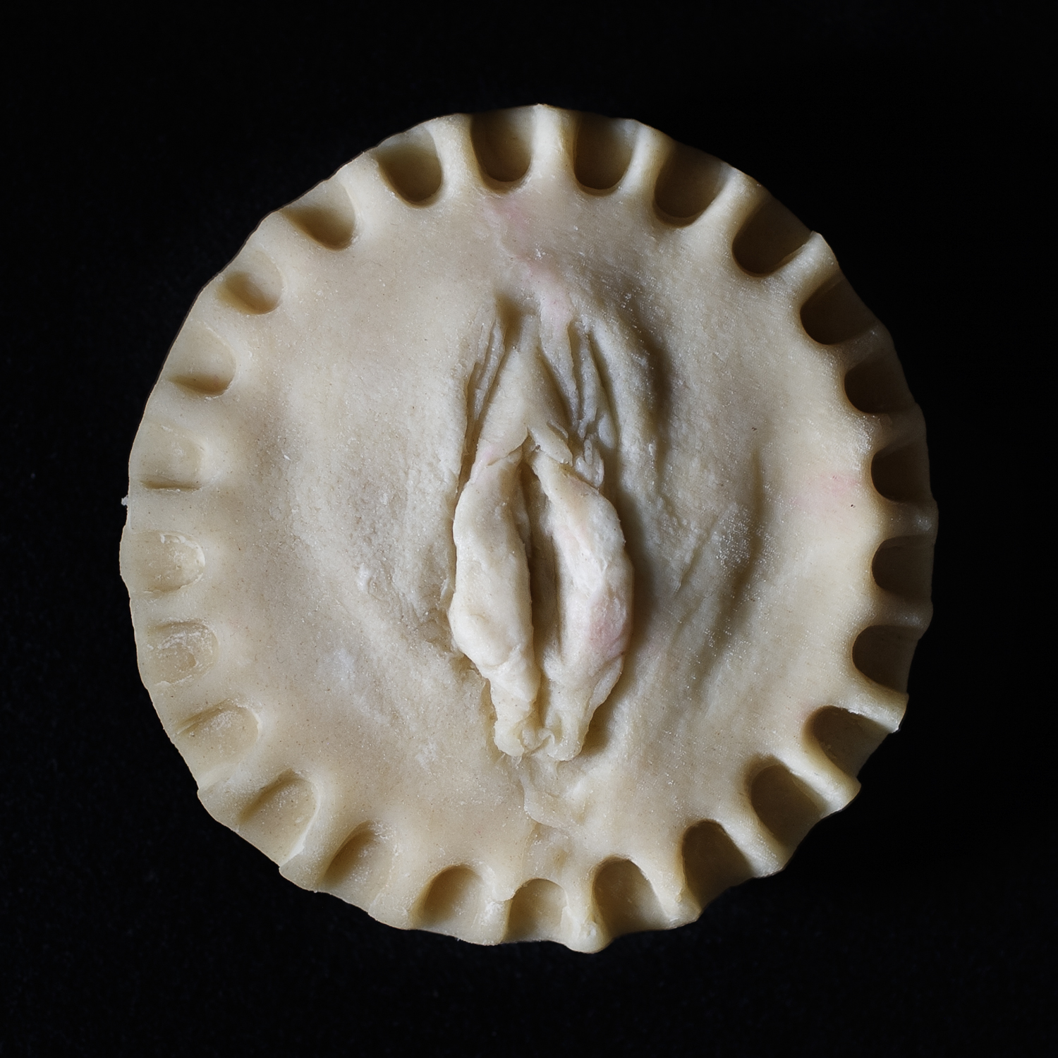 Made from scratch vulva pie on black background. 