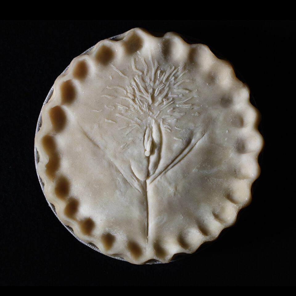 Unbaked pie with hand sculpted art made to look like a vulva