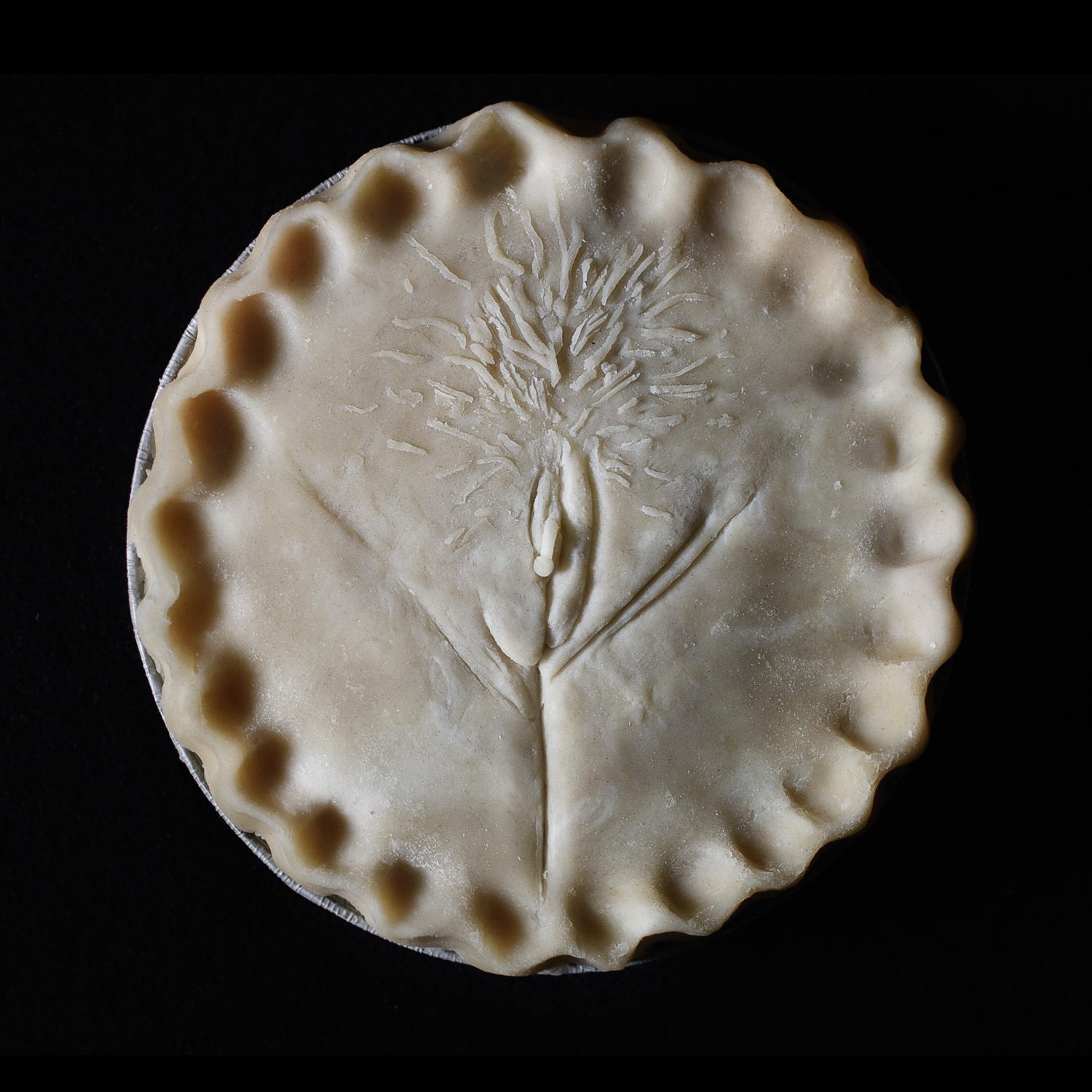 Unbaked pie with hand sculpted art made to look like a vulva