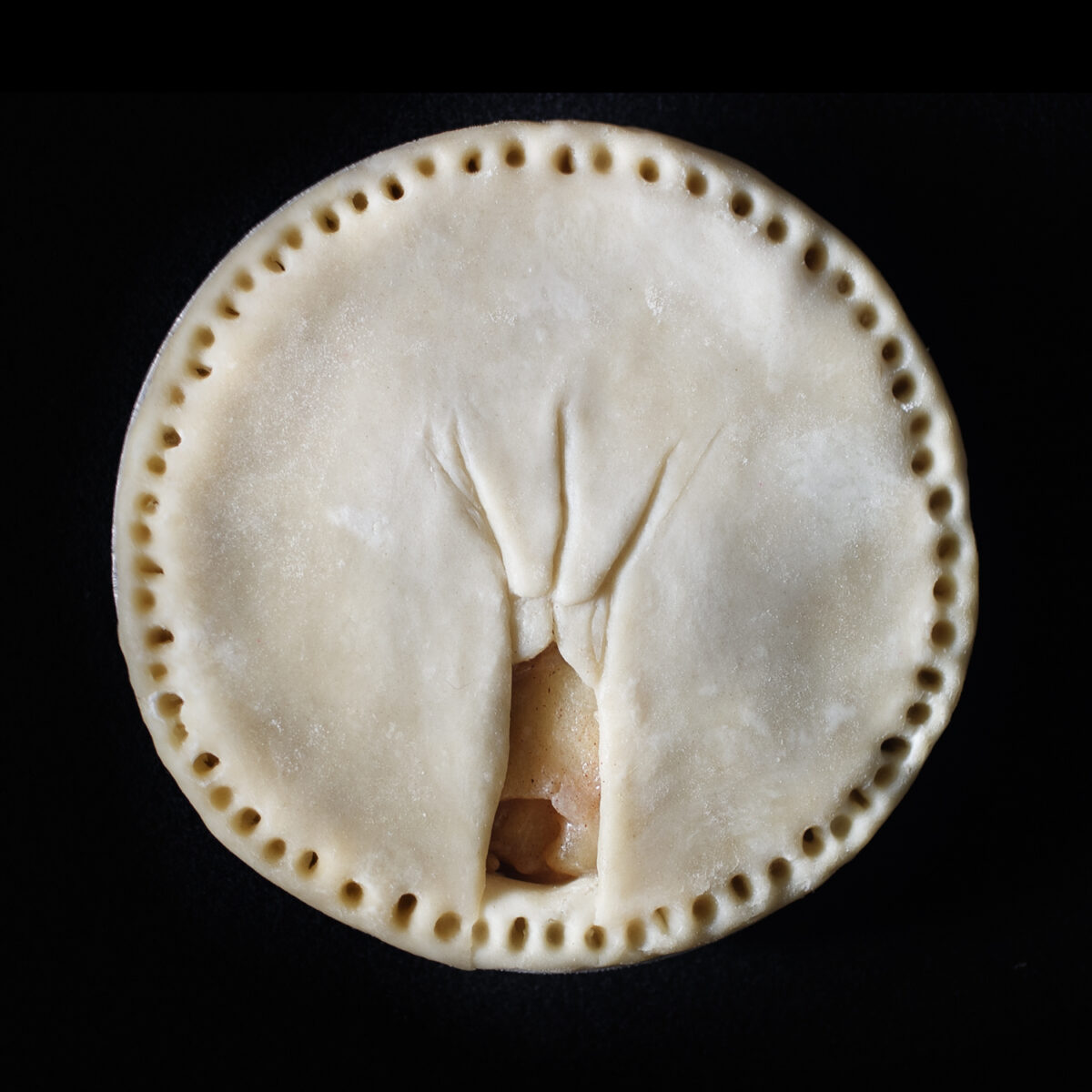 Unbaked pie 88 on a black background. Pie was made as a sculpture and portrait of a human vulva