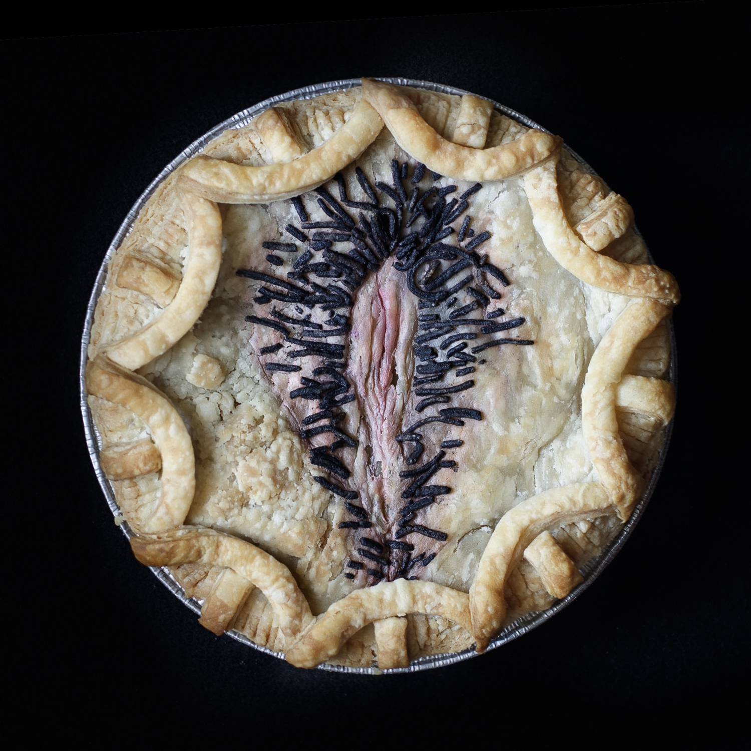 baked vulva art pie on a black background 